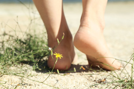 Woman walking barefoot on sand outdoors, closeupの写真素材