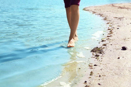 Woman walking barefoot through water on riverbank, closeupの写真素材