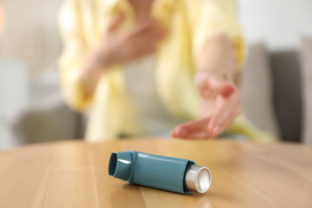 Young woman with asthma inhaler at table, selective focusの写真素材