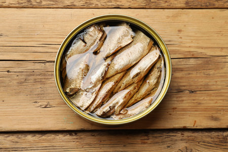 Tasty sprats in tin can on wooden table, top viewの写真素材
