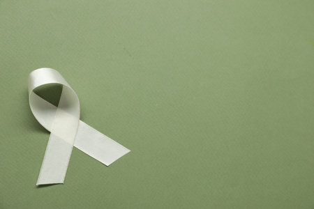 White awareness ribbon on green background, top view. Space for textの写真素材