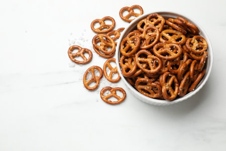 Tasty pretzel crackers with salt on white marble table, top view. Space for textの写真素材