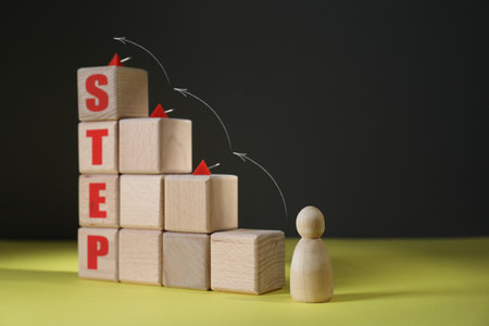 Human figure in front of wooden cubes stair with pins and word Step on yellow table. Arrows showing...