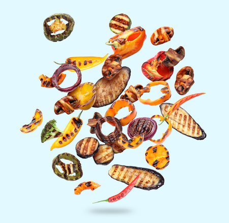 Tasty grilled vegetables in air on light blue backgroundの写真素材