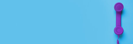 Purple corded telephone handset on light blue background, top view. Banner design with space for...