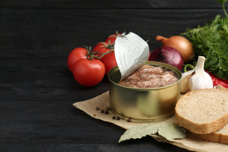 Canned meat in tin can and other products on wooden table. Space for textの写真素材