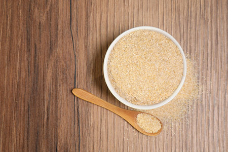 Oat bran in bowl and spoon on wooden table, top view. Space for text