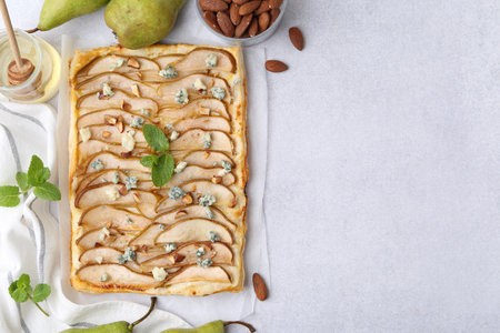 Delicious puff pastry tart with pears, almond, mint and blue cheese on light table, flat lay. Space for textの写真素材