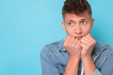 Portrait of scared young man on light blue background, space for textの写真素材