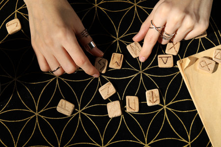 Woman with wooden runes at divination mat, top view