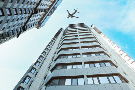 Airplane flying over buildings in city, low angle viewの写真素材