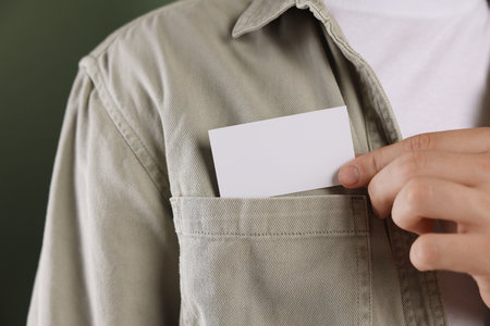 Man taking blank business card from pocket of his jacket on green background, closeup. Mockup for designの写真素材