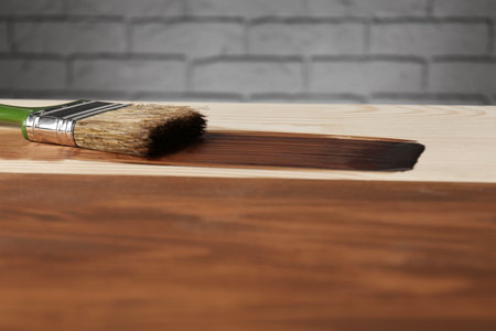 Applying walnut wood stain. Brush on wooden surface, closeupの写真素材