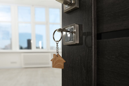 Open door with key and house shaped keychain, closeup. Space for textの写真素材