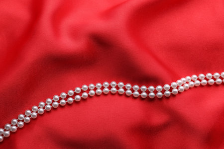 Beautiful pearl necklace on red cloth, top viewの写真素材