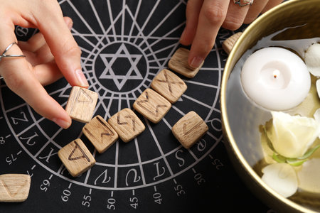 Woman with wooden runes at divination mat, top view