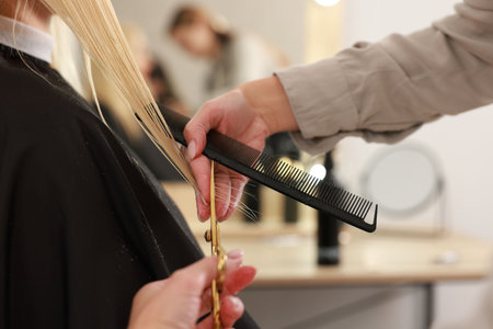 Hairdresser cutting client's hair with scissors in salon, closeupの写真素材