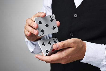Professional croupier shuffling cards on gray background
