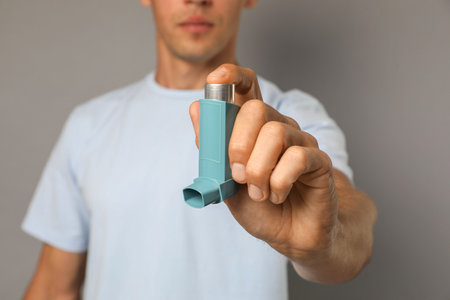 Man holding asthma inhaler on gray background, closeupの写真素材