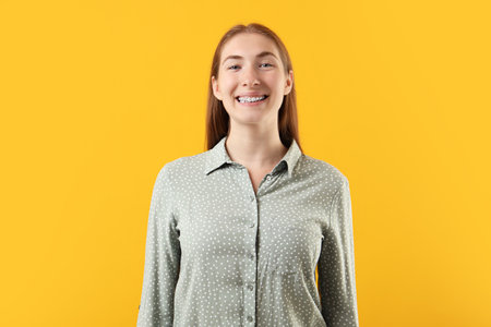Smiling girl with braces on orange backgroundの写真素材