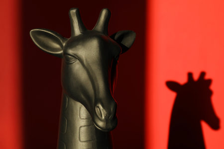Decorative figure of giraffe casting shadow on red background, closeupの写真素材