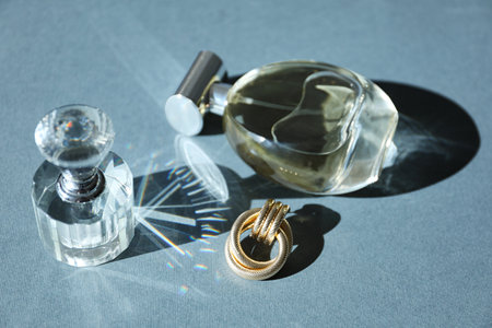 Perfume bottles and stylish earring on gray backgroundの写真素材