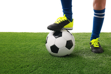 Football player with soccer ball on artificial grass against white background, closeupの写真素材