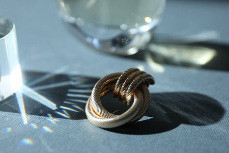 Perfume bottles and stylish earring on gray background, closeup