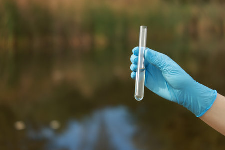 Examination of water quality. Researcher holding test tube with sample outdoors, closeup. Space for textの写真素材