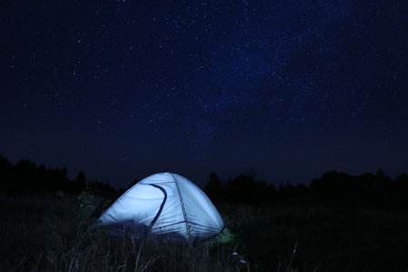 Modern camping tent in wilderness at nightの写真素材