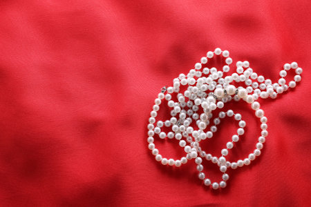 Beautiful bijouterie with pearls on red cloth, top view. Space for textの写真素材
