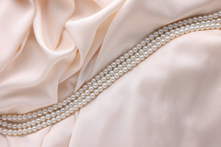 Beautiful pearl necklace on beige cloth, top viewの写真素材