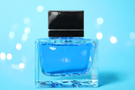 Perfume bottle on light blue background with blurred lights, closeupの写真素材