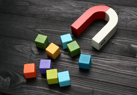 Magnet attracting colorful cubes on wooden tableの写真素材