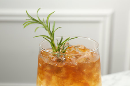 Refreshing espresso tonic drink with rosemary on blurred background, closeup