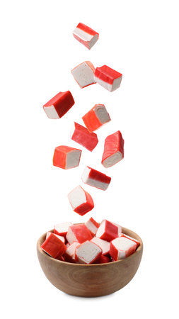 Crab stick pieces falling into bowl on white backgroundの写真素材