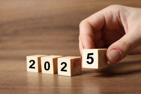 2025 New Year. Woman putting wooden cube with number 5 on table, closeupの写真素材