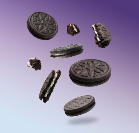 Tasty broken sandwich cookies in air on purple gradient backgroundの写真素材
