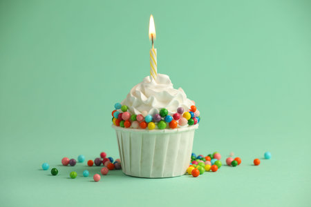 Birthday cupcake with burning candle on turquoise backgroundの写真素材