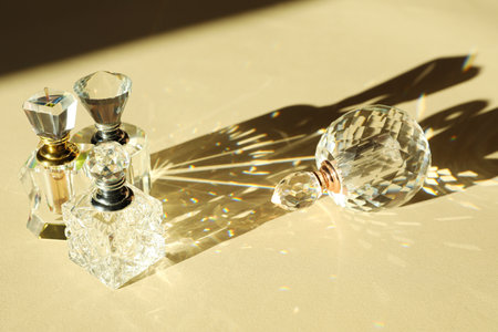 Many perfume bottles casting beautiful shadows on beige background, closeup