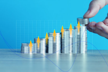 Investment. Woman stacking coins on light blue background, closeup. Arrows and graphの写真素材