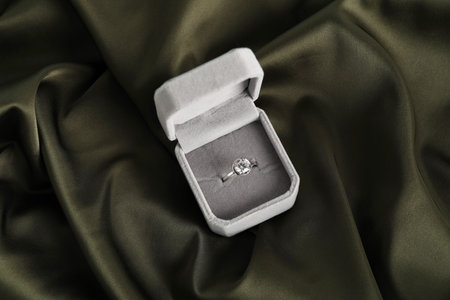 Beautiful ring with gemstone in box on dark fabric, top view