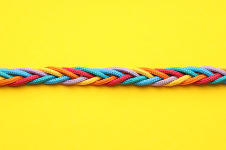 Braided colorful ropes on yellow background, top view. Unity conceptの写真素材