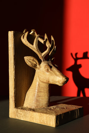 Decorative figure of deer on black table against red background with shadowの写真素材