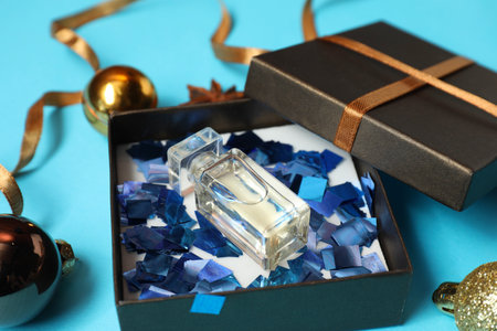Perfume bottle in gift box and Christmas decor on light blue background, closeupの写真素材