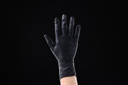 Man wearing latex glove on black background, closeupの写真素材