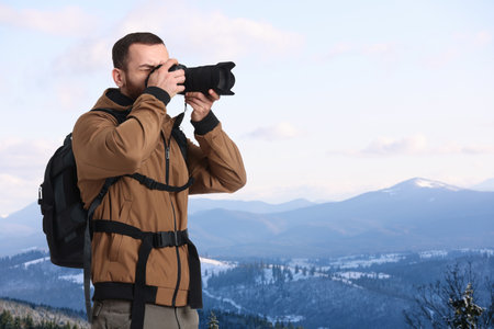 Man with backpack taking photo in mountainsの写真素材