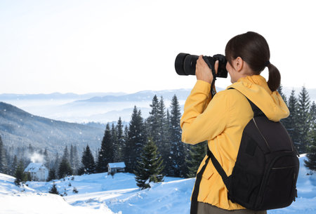 Woman with backpack taking photo in mountainsの写真素材