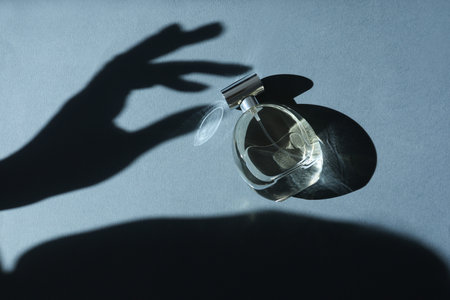 Perfume bottle and shadow of woman's hand on gray background, top viewの写真素材