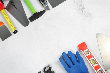 Many different construction tools on light textured table, flat lay. Space for text
